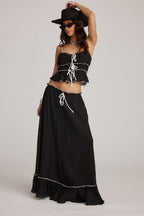 Conjunto de falda y top negro con volantes y cordones blancos en el pecho