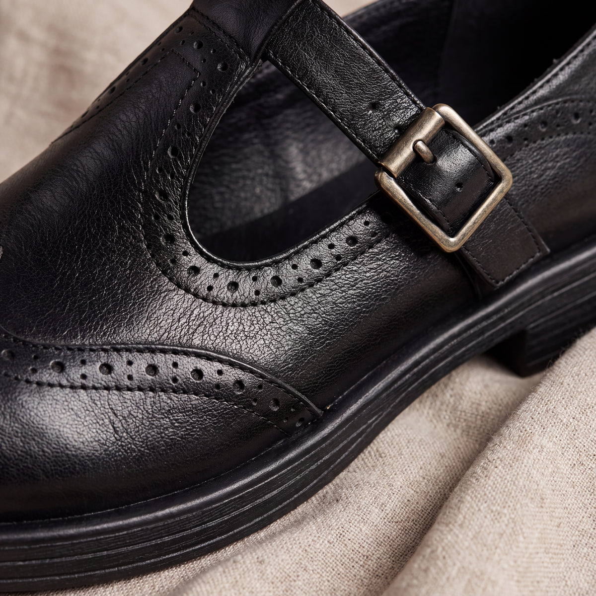 Mocasín Louisa™ de cuero negro con perforaciones y hebilla metálica, detalle