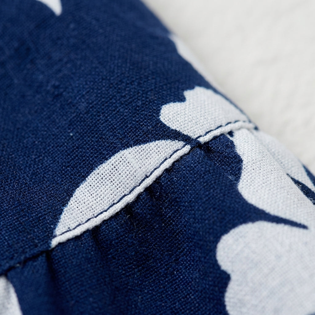 Detalle de tela de falda plisada azul marino con estampado floral blanco