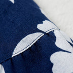 Detalle de tela de falda plisada azul marino con estampado floral blanco