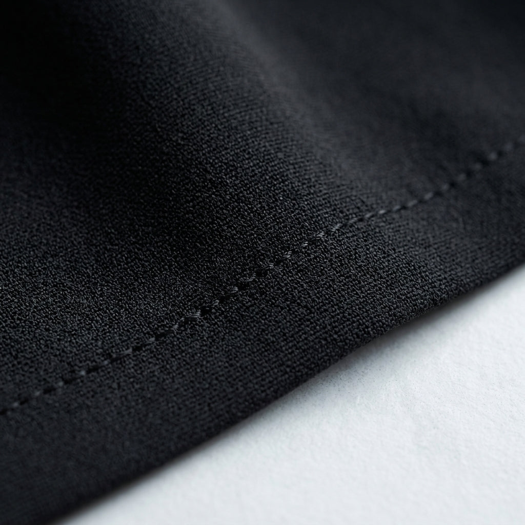 Tela negra del vestido Aura, con costura visible y textura tipo sarga.