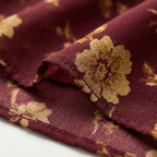 Vestido de tela granate con estampado dorado, detalle con costura y pliegues