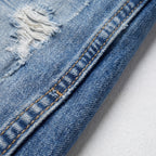 Detalle de costura en vaquero azul claro con pespuntes y desgaste en la tela