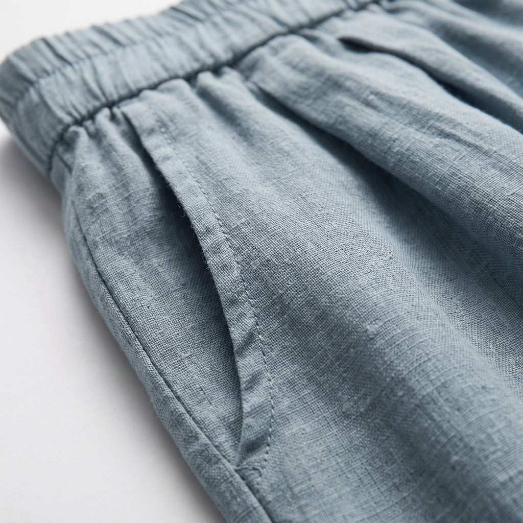 Pantalón corto de lino azul celeste con fruncido en la cintura y textura de tejido.