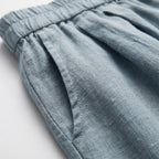 Pantalón corto de lino azul celeste con fruncido en la cintura y textura de tejido.