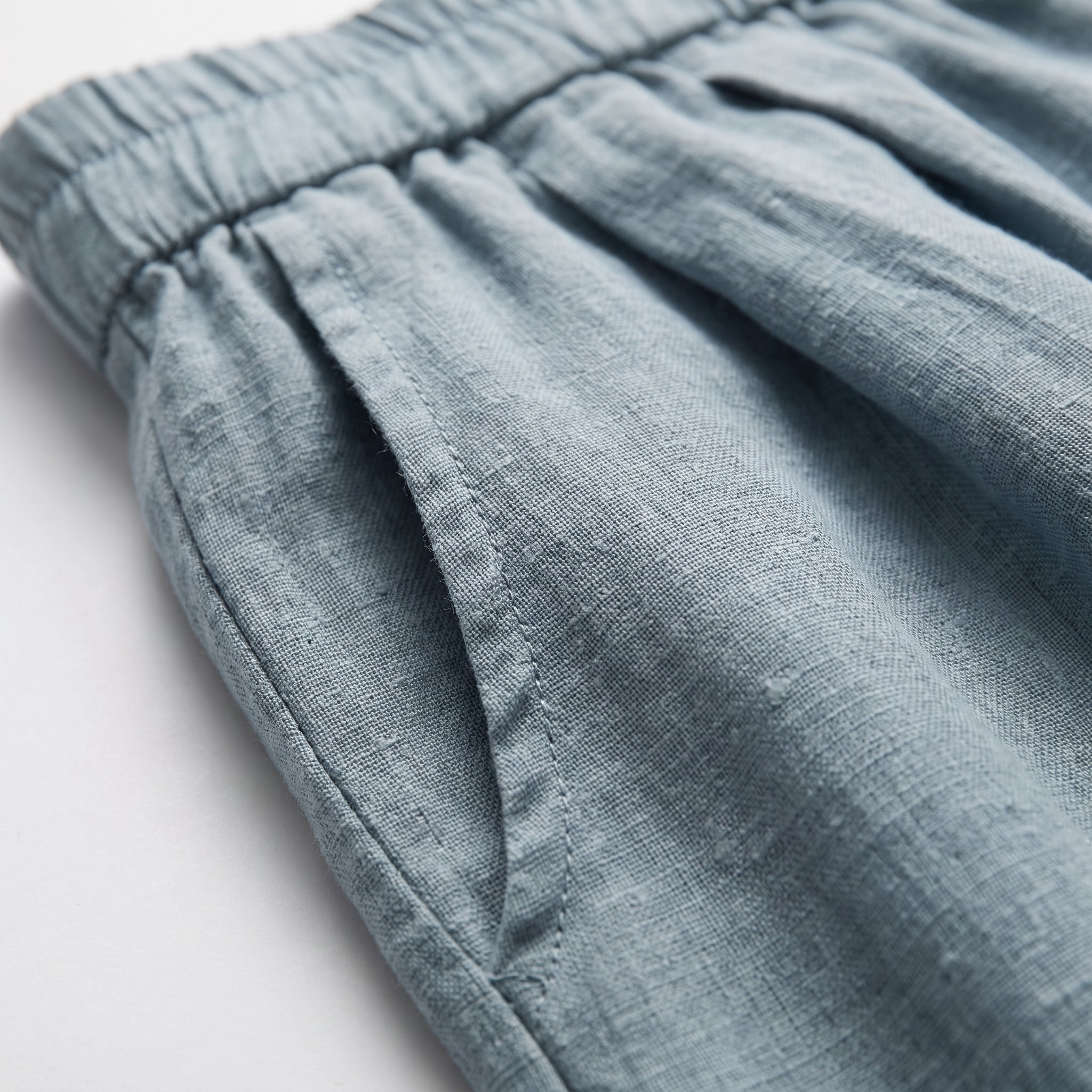 Pantalón corto de lino azul celeste con fruncido en la cintura y textura de tejido.