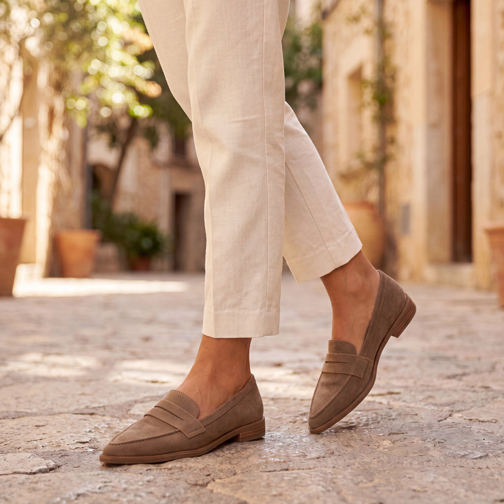Mocasines de ante color taupe con tira al empeine y suela marrón, estilo casual.