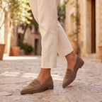 Mocasines de ante color taupe con tira al empeine y suela marrón, estilo casual.