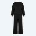 Conjunto de suéter y pantalón negro con brillo sutil; pantalón ancho con cordón.