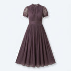 Vestido Lumière viola con encaje floral en cuello y mangas, falda plisada.