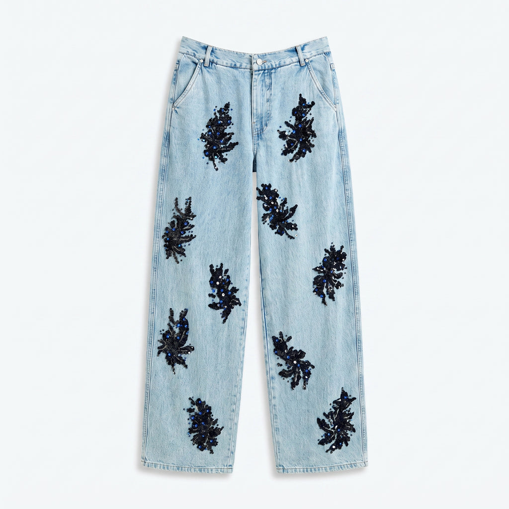 Vaqueros de denim azul claro con apliques negros tipo flor en toda la pierna