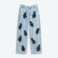 Vaqueros de denim azul claro con apliques negros tipo flor en toda la pierna