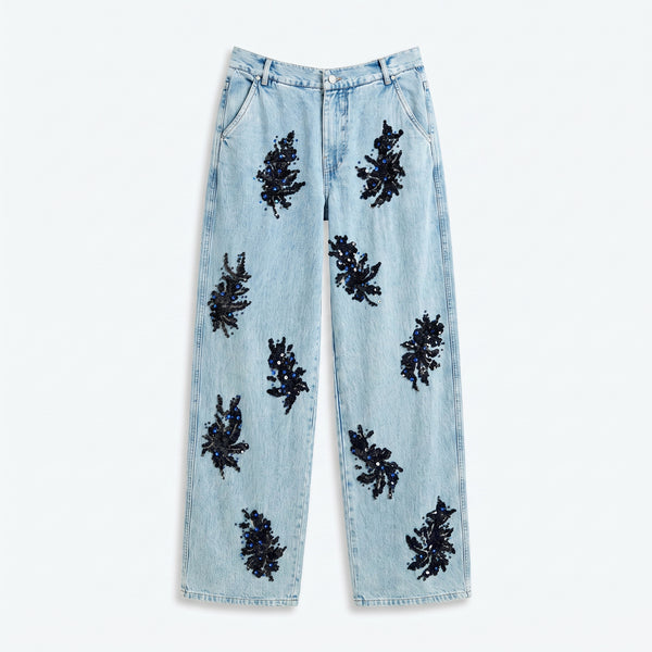 Vaqueros de denim azul claro con apliques negros tipo flor en toda la pierna