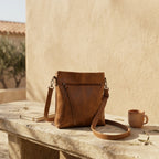 Bolso bandolera marrón con correa de piel y cierre con cremallera, con forma estructurada.