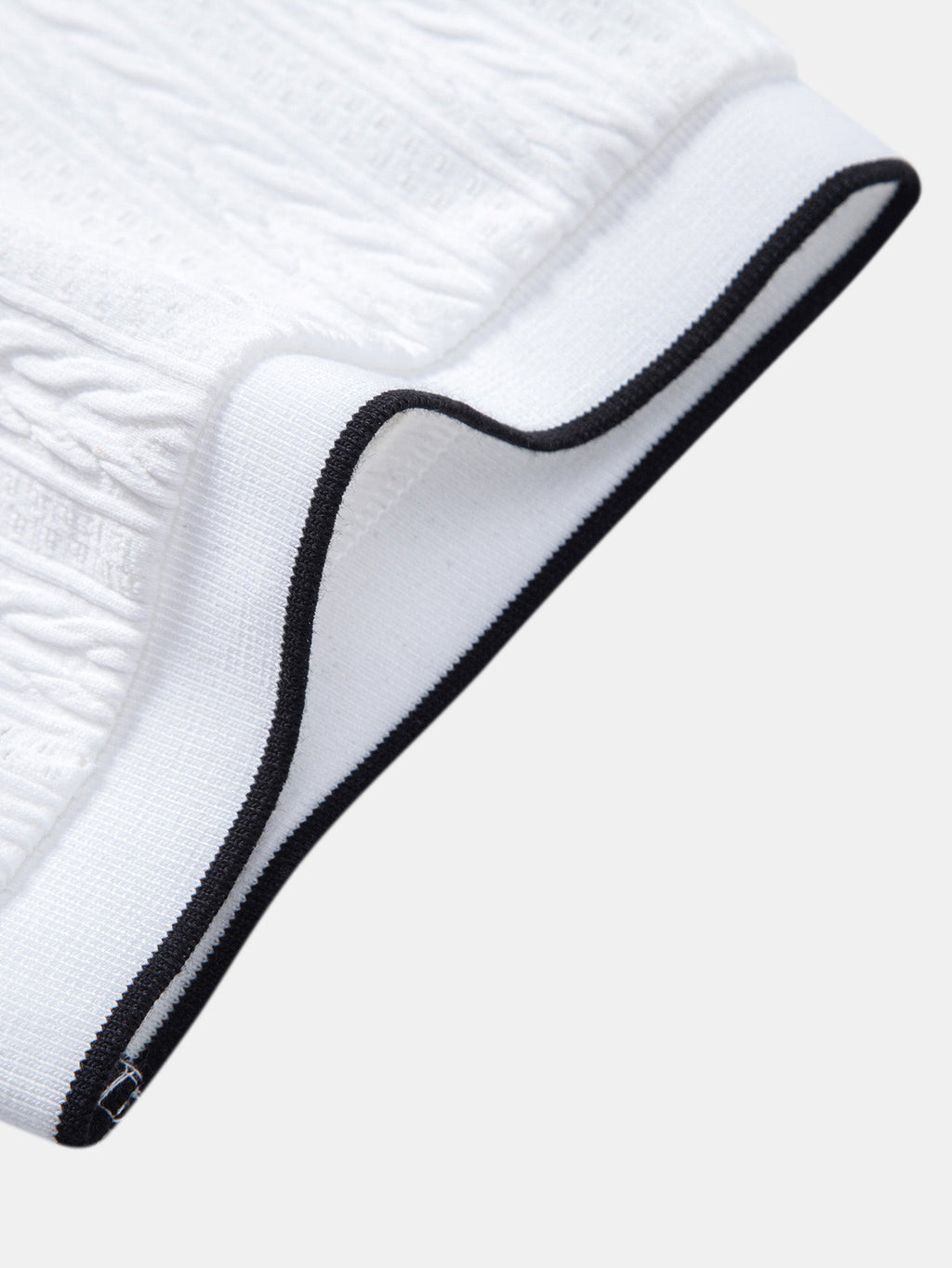 Polo blanco con vivos negros en cuello y tejido texturizado