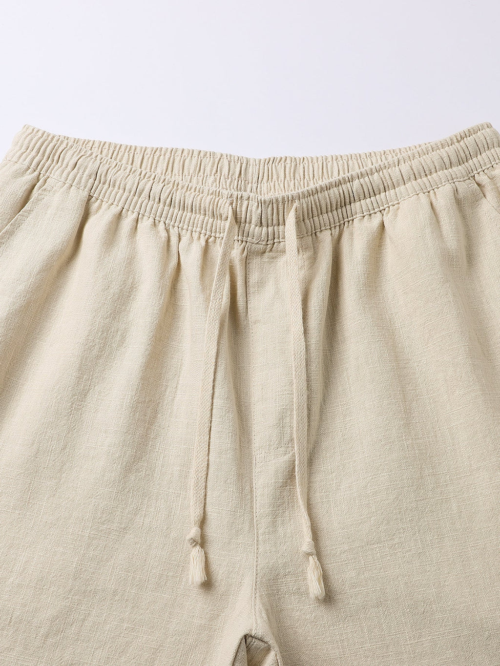 Pantalón corto de lino beige, cintura elástica y cordón anudado, vista frontal.