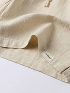 Pantalón corto de lino beige, dobladillo y etiqueta en el bajo, con cordón.