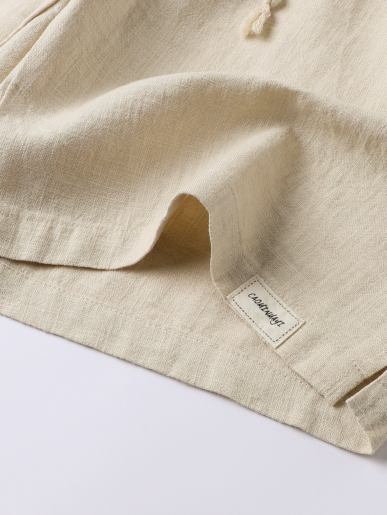 Pantalón corto de lino beige, dobladillo y etiqueta en el bajo, con cordón.