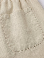 Pantalón corto de lino beige con bolsillo delantero y costuras visibles.