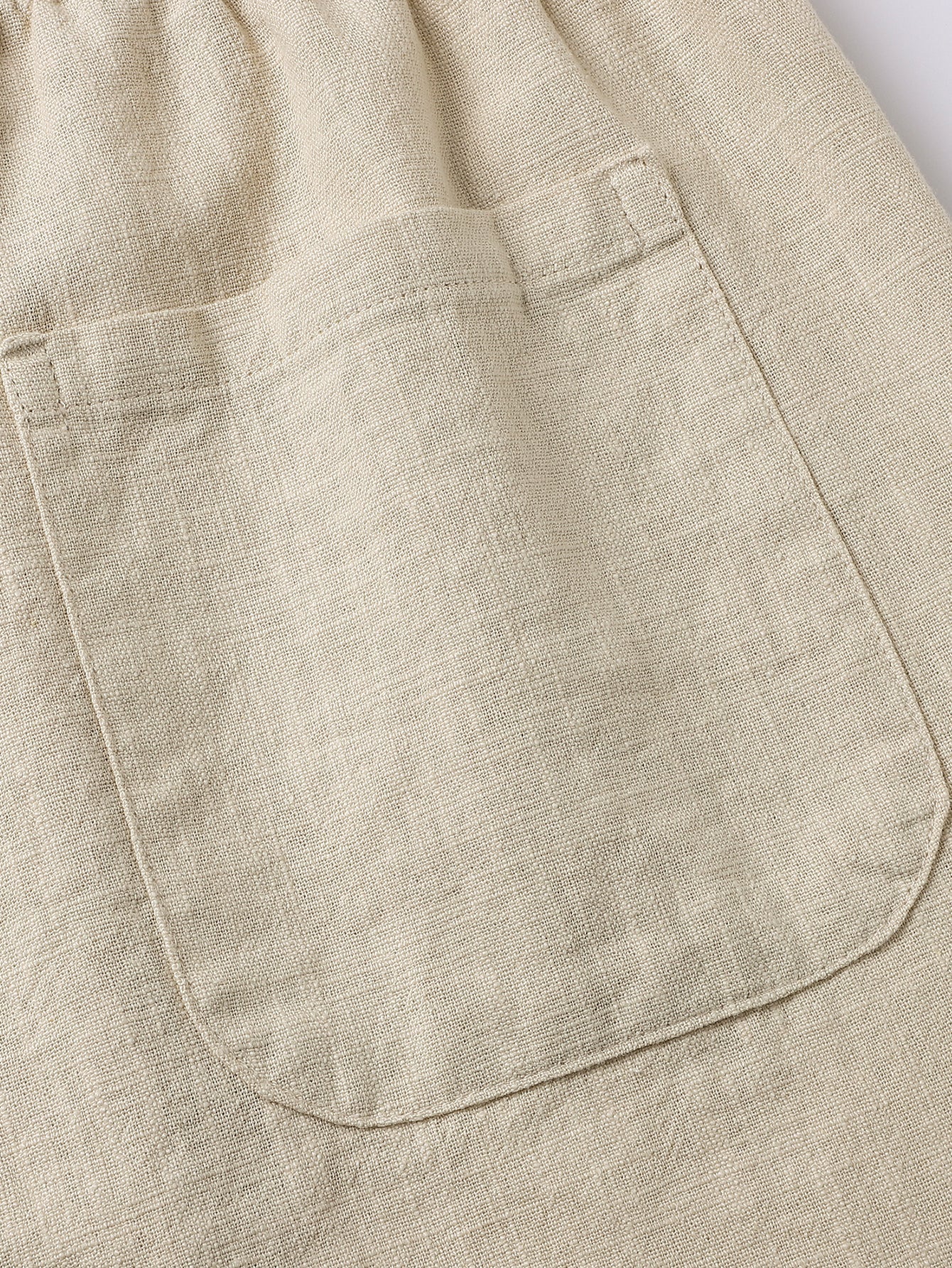 Pantalón corto de lino beige con bolsillo delantero y costuras visibles.