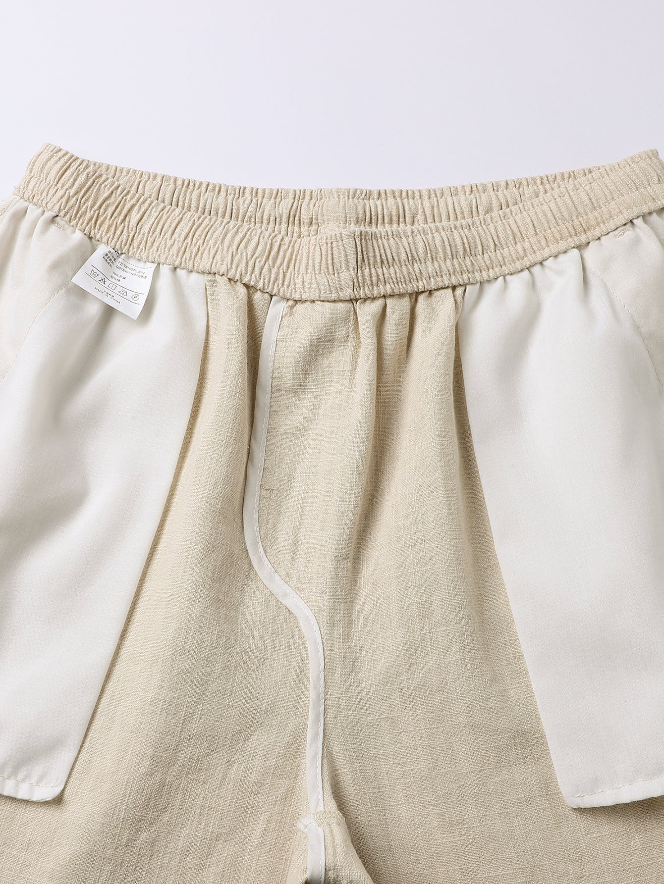 Pantalón corto de lino beige con cintura elástica, cordón y etiqueta interior visible.