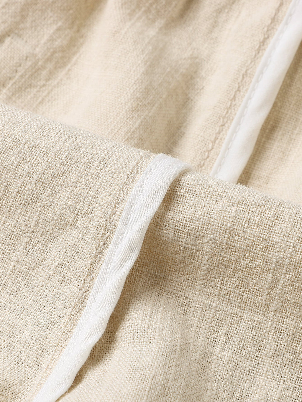 Pantalón corto de lino beige con costuras y cordón en la pretina, detalle de tejido.
