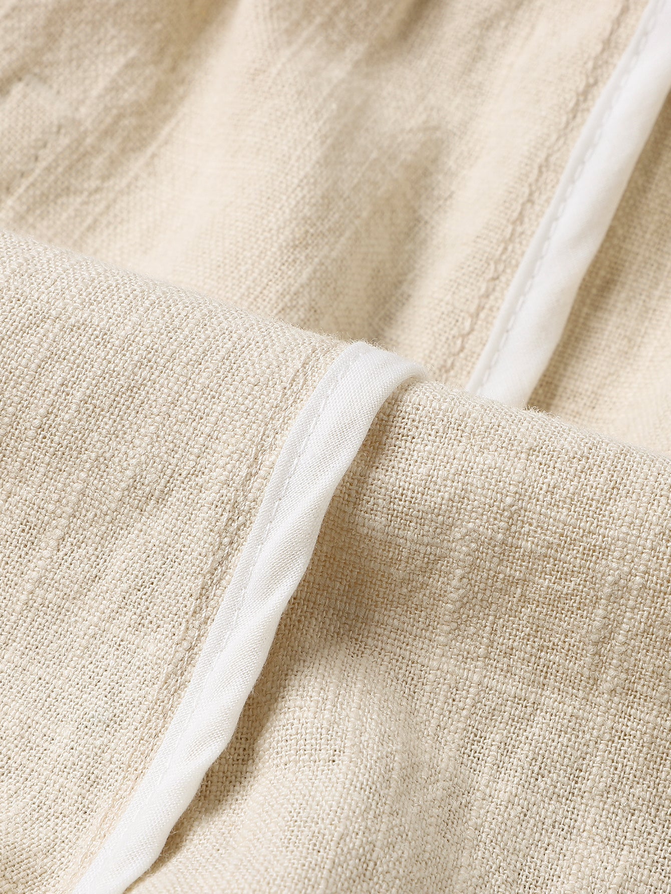 Pantalón corto de lino beige con costuras y cordón en la pretina, detalle de tejido.