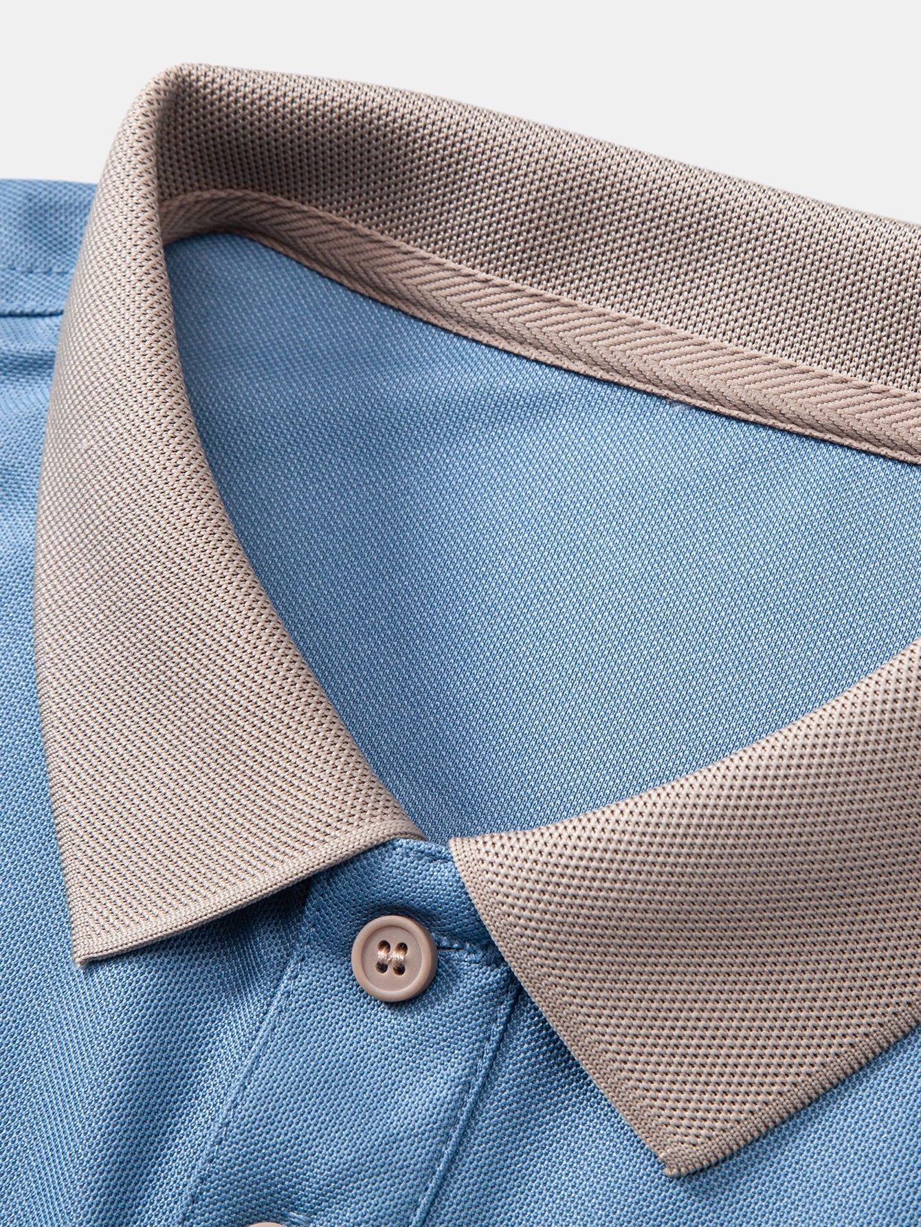 Detalle de cuello y tapeta: polo azul claro con ribete beige y botón
