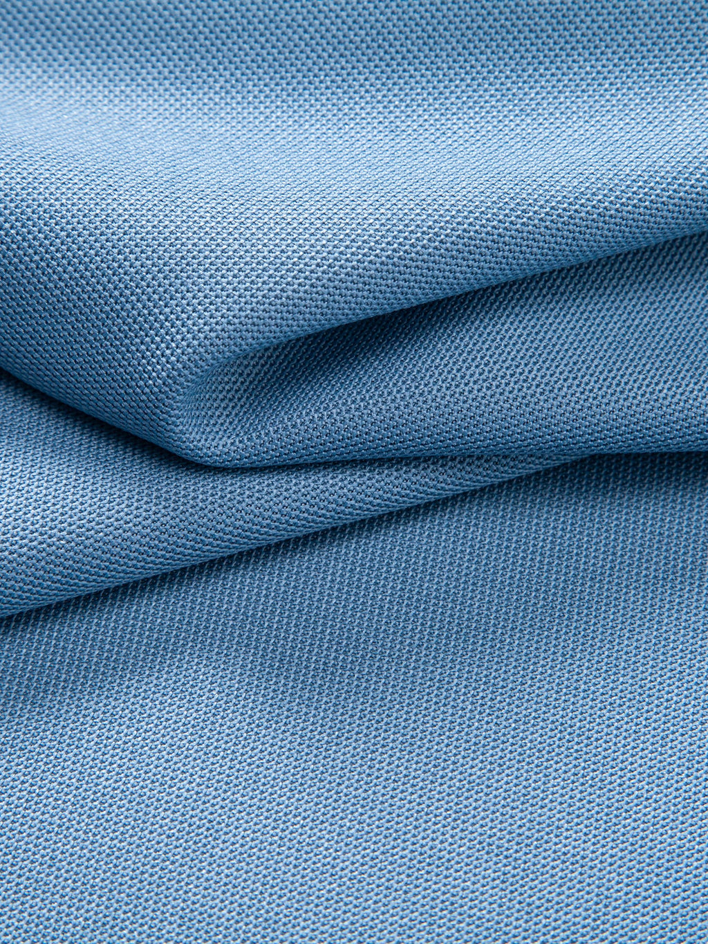 Polo azul claro con tejido tipo piqué, pliegues y textura visible