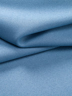 Polo azul claro con tejido tipo piqué, pliegues y textura visible