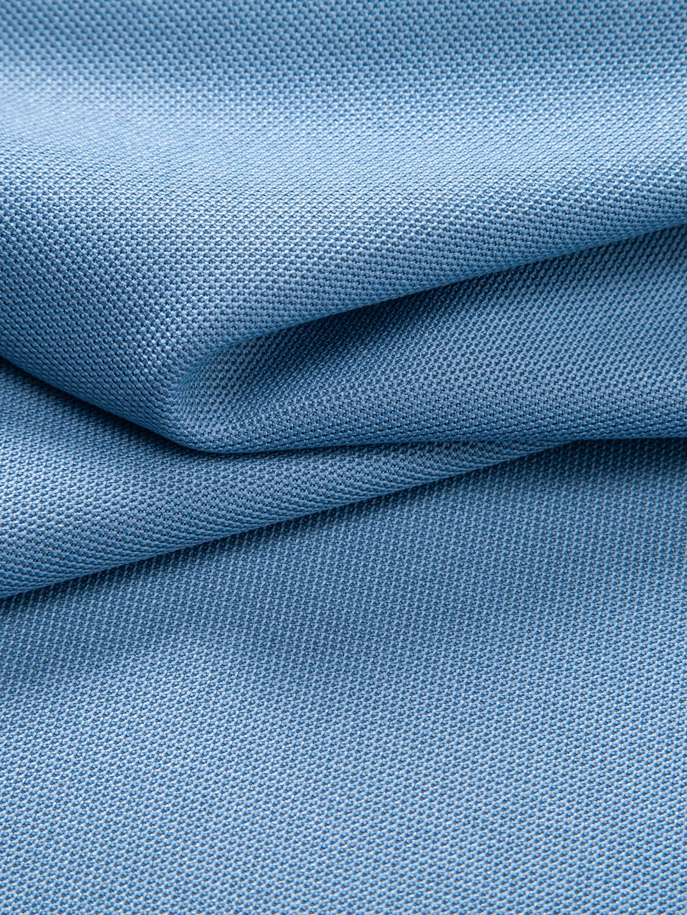 Polo azul claro con tejido tipo piqué, pliegues y textura visible