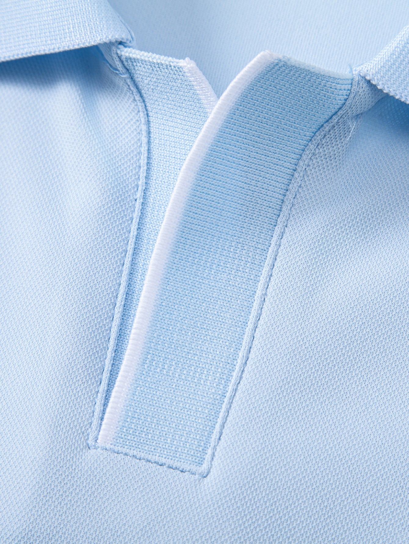 Polo celeste: costuras de la tapeta y botones en la pechera, vista detalle.