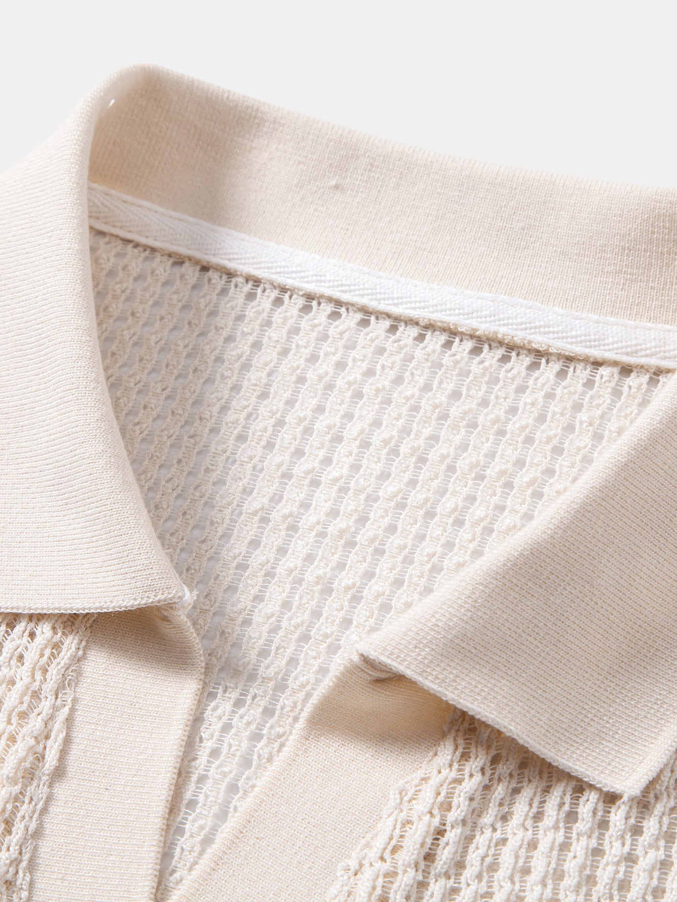 Cuello del polo beige en V y borde acanalado con tejido calado