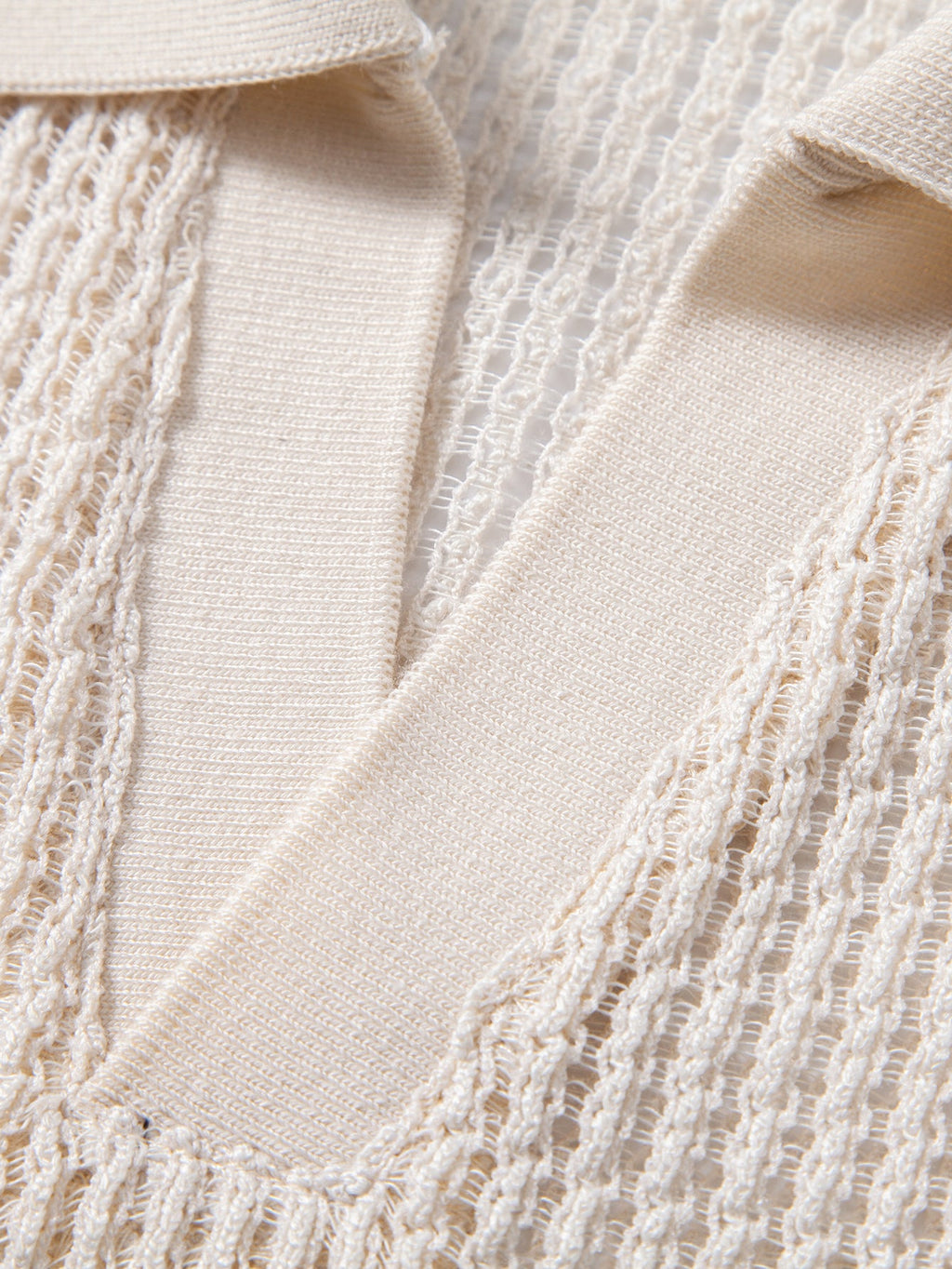 Detalle del polo beige con solapa en V y textura de punto calado