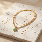 Collar dorado con cadena trenzada y colgante circular verde claro