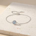Pulsera de plata con piedra central redonda transparente en bisel.