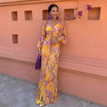 Vestido largo amarillo con escote profundo, estampado floral y mangas acampanadas