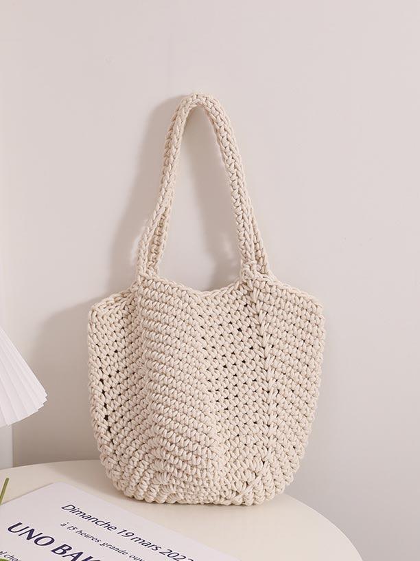 Bolso tote de tejido de rafia, color crudo, asas de cuerda y forma redondeada.