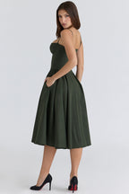 Vestido verde oscuro con tirantes finos y falda amplia plisada, hasta la rodilla.