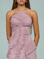 Detalle de vestido rosa con tirante cruzado halter y volantes fruncidos en el corpiño.