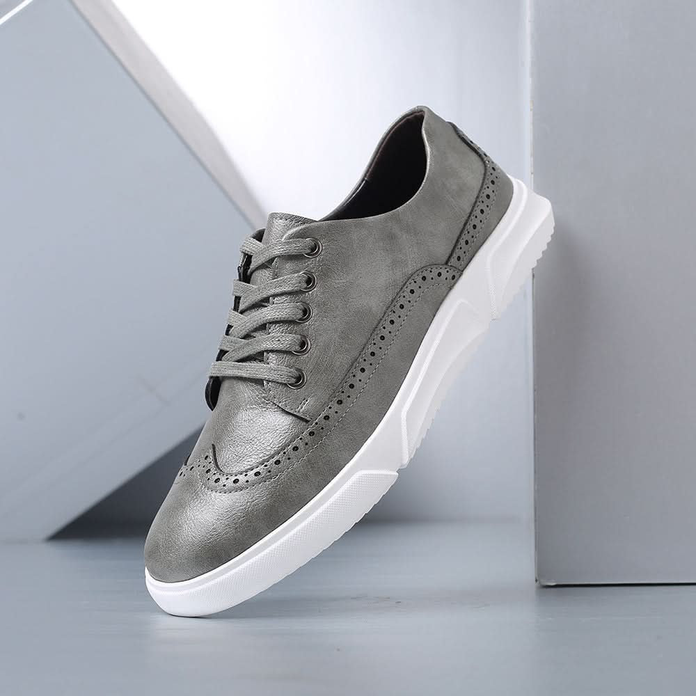 Zapatillas tipo brogue de cuero gris con ojales decorados, cordones y suela blanca