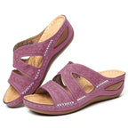 Sandalias de cuero morado con tiras caladas y costuras blancas, suela marrón