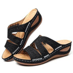 Sandalias de tiras negras con cuña, vista lateral, calados florales y costuras blancas