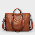 Bolso marrón de piel con doble asa, cremallera central y correa ajustable cruzada.