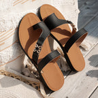 Chanclas Nora negras con suela de cuero y tiras cruzadas con herraje plateado