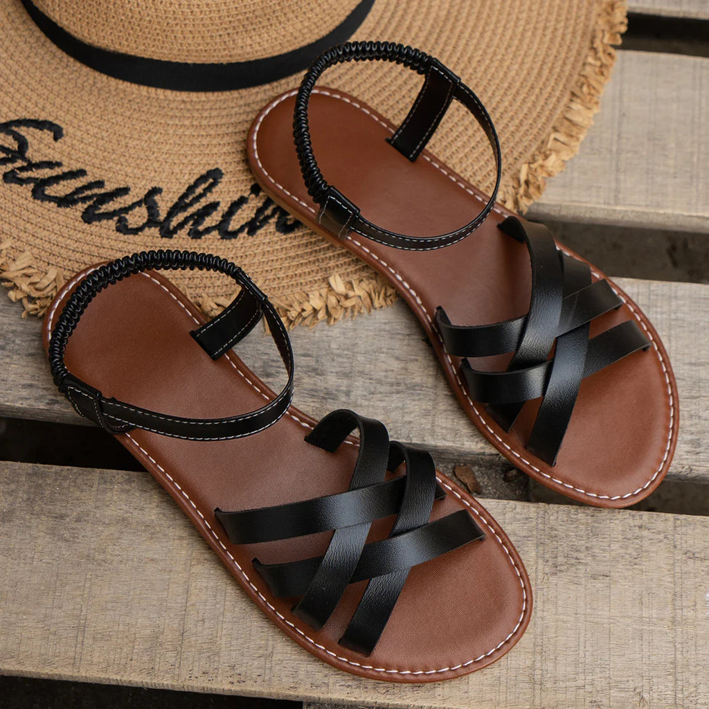 Sandalias negras de tiras cruzadas con hebilla y suela plana.