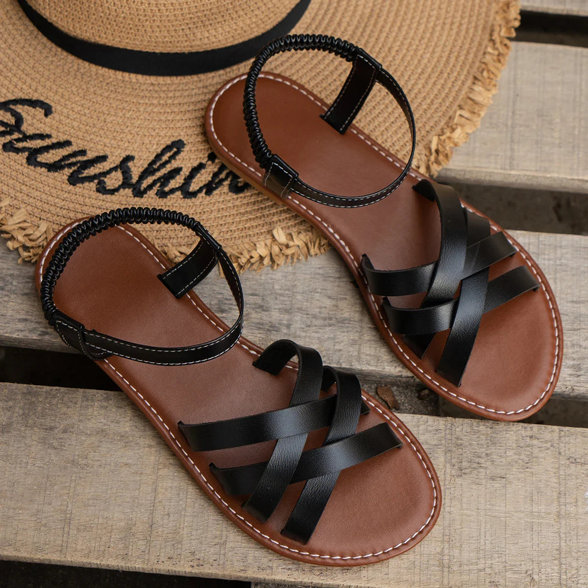 Sandalias negras de tiras cruzadas con hebilla y suela plana.