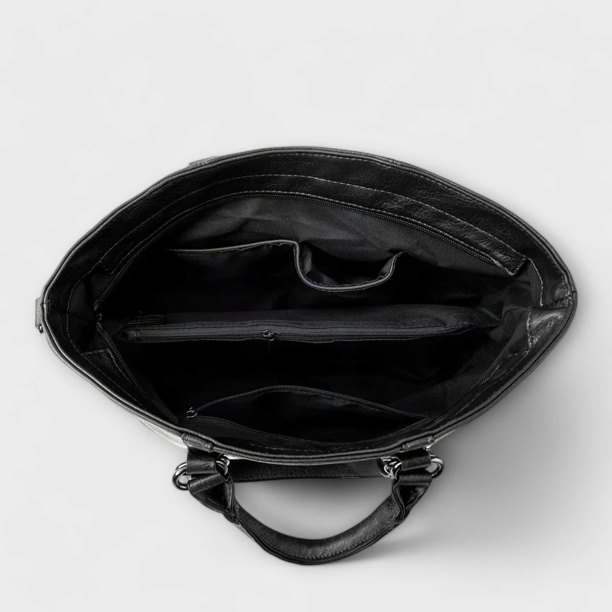 Bolso negro abierto, interior forrado con compartimentos y cremallera superior.