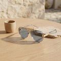 Gafas de sol con montura transparente y lentes azules, con patillas doradas