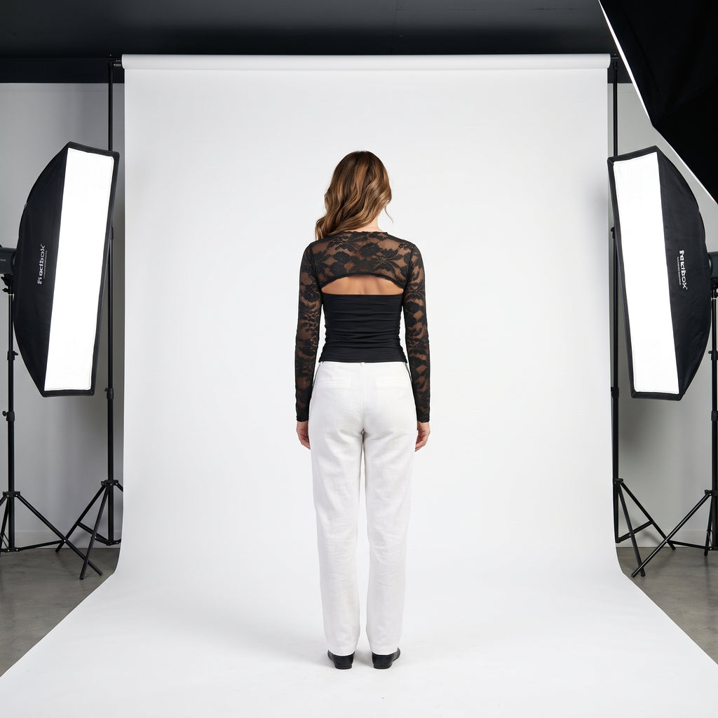 Top negro de encaje floral con panel liso y manga larga transparente, escote tipo barco